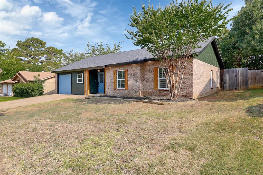 Single-story brick exterior featuring wooden shutter accents, an attached garage, and a timber privacy fence