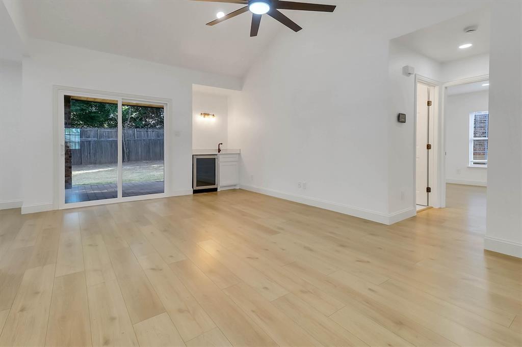 Vaulted ceilings, wood-finish flooring, built-in wet bar with under-counter beverage refrigerator, and sliding glass doors