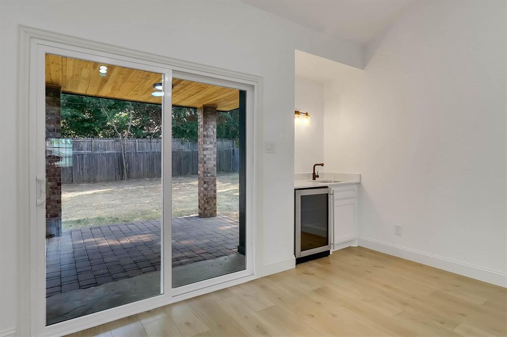 Sliding glass door leading to a covered brick patio with a wood-plank ceiling