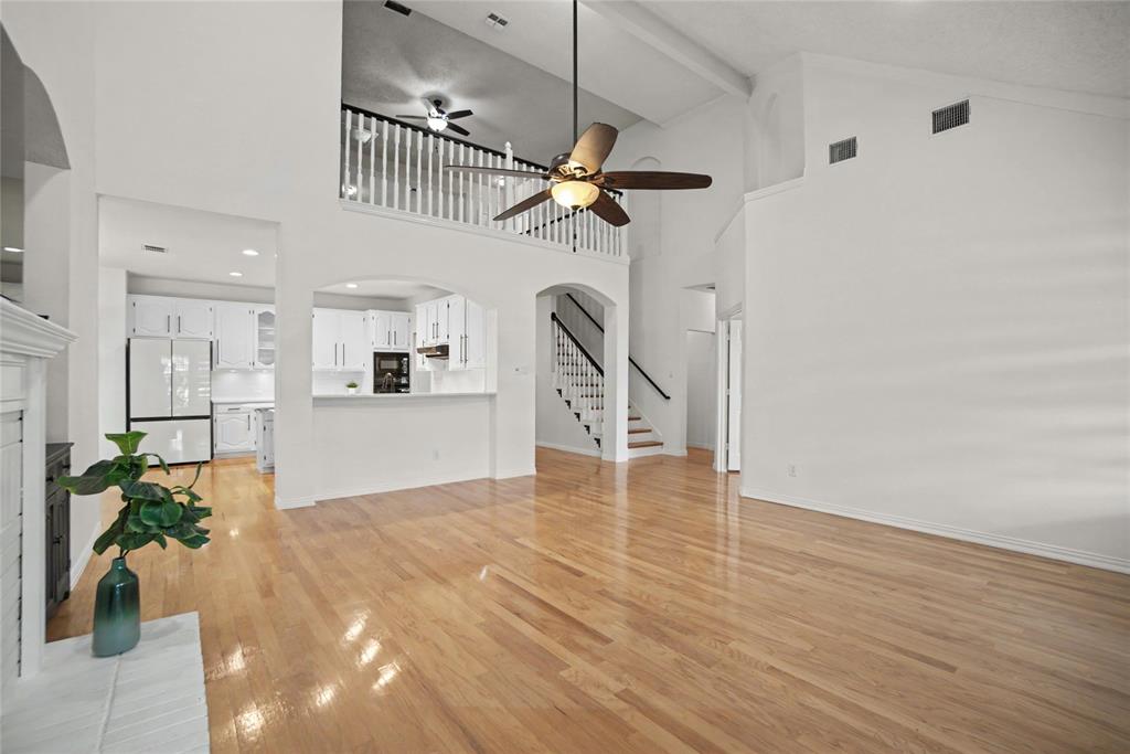 A spacious family room with 2 story high ceilings- a view of the 2nd floor overlooks. Open to the breakfast bar, kitchen with hardwood floors.