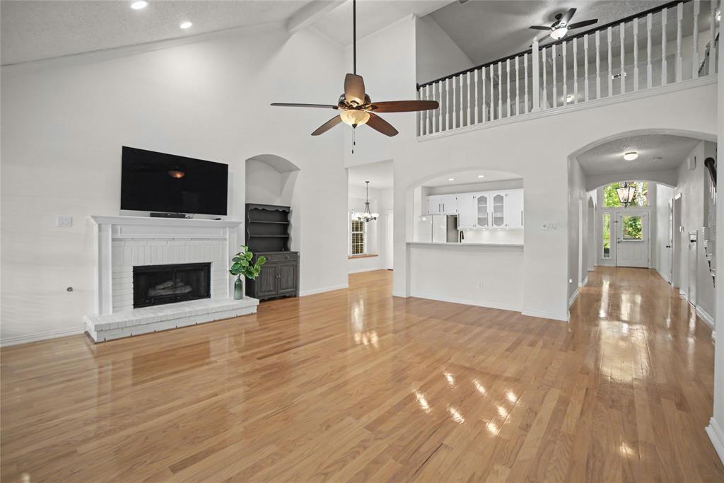 A spacious family room has tall panel windows and a mantled corner fireplace.