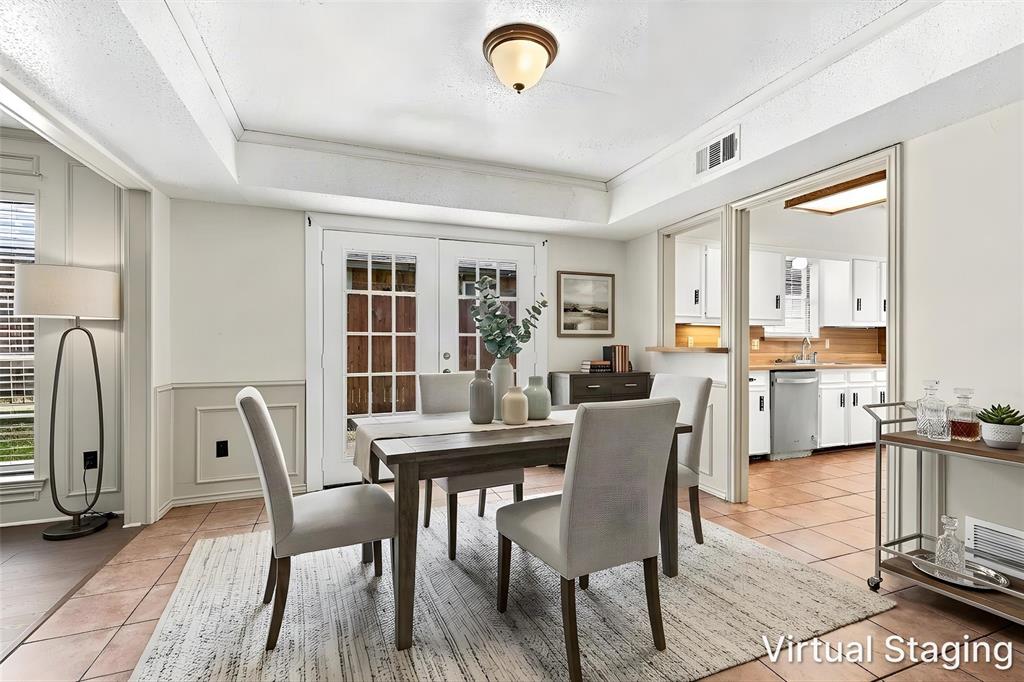 Dining area featuring dual-pane French doors with muntins, tiled flooring, crown molding, and wainscoting