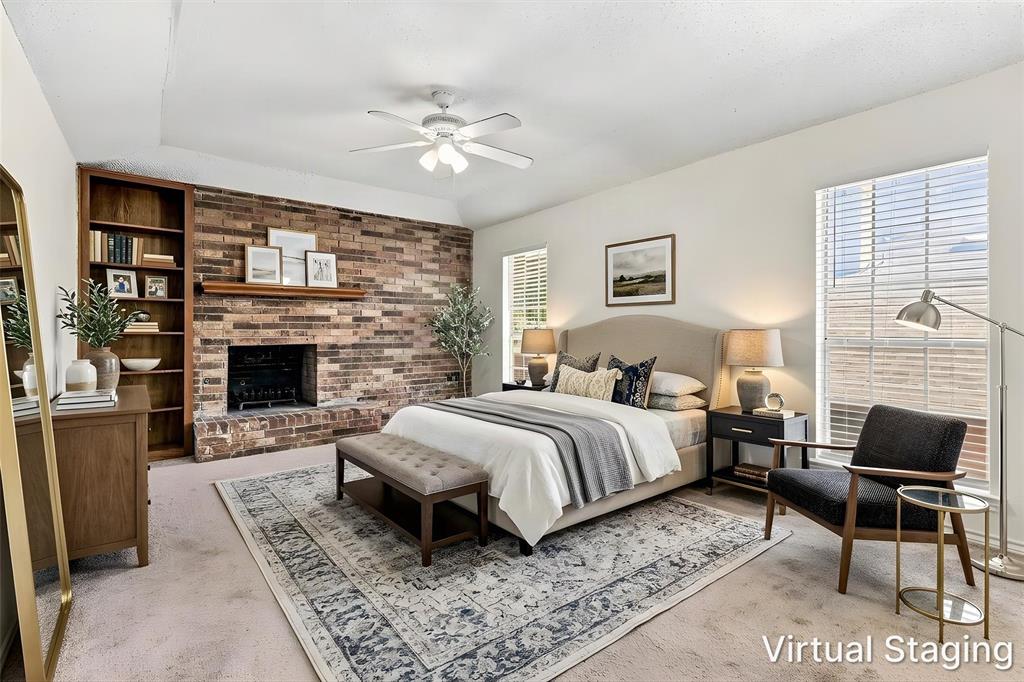 Exposed brick fireplace with a wood mantel, built-in floor-to-ceiling shelving, tray ceiling, and a ceiling fan with integrated lighting