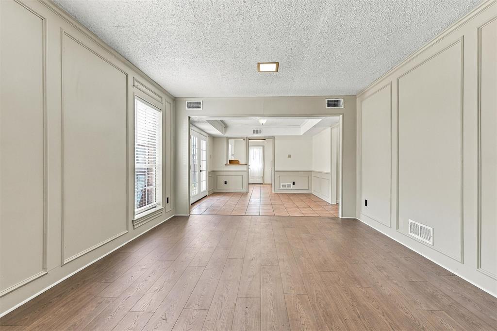 Room featuring wood-finish flooring, decorative wall molding, and tiled surfaces with French doors