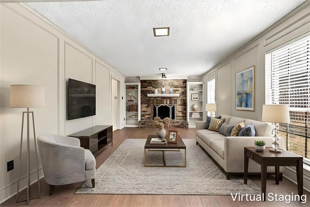 Living room featuring paneled walls, wood-finish flooring, a brick fireplace with a mantel, and built-in shelving