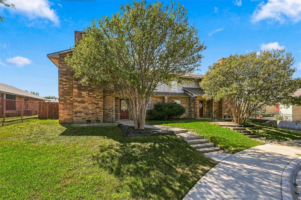 Multi-level brick exterior featuring concrete stairs, mature landscape trees, and a concrete walkway Multi-level brick exterior featuring concrete stairs, mature landscape trees, and a concrete walkway
