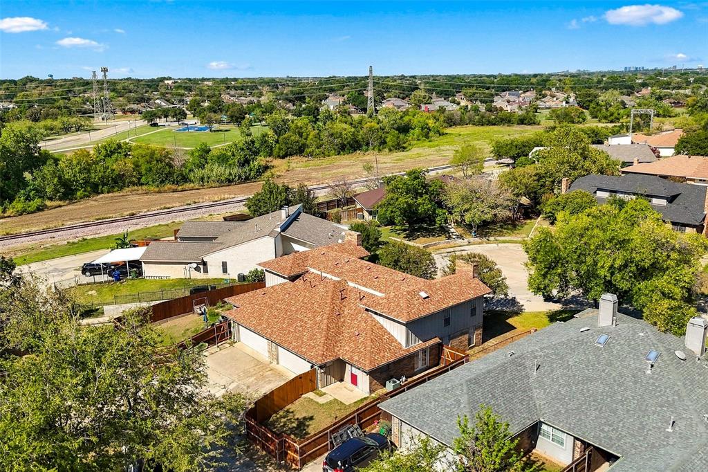 Aerial perspective featuring a multi-level residence with a multi-gabled shingle roof, attached garage, and a fenced backyard