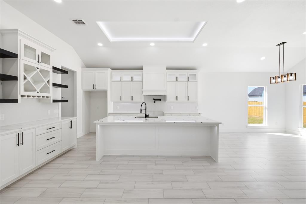 Kitchen featuring white cabinetry, center island with stone-finish countertop, built-in wine rack, recessed ceiling lighting, and wood-finish tile flooring