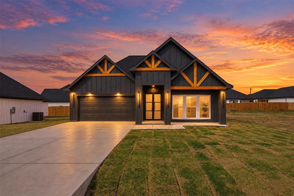 Modern exterior featuring dark board-and-batten siding, decorative wood gable accents, a concrete driveway, and a double-door entrance