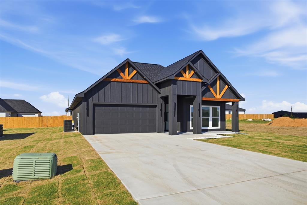 Single-story exterior featuring dark vertical siding, contrasting wood-finish gables, a concrete driveway, and an attached two-car garage