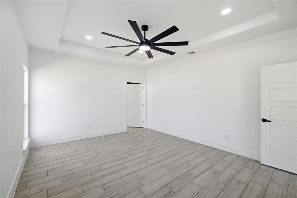 Tray ceiling featuring a multi-blade matte black ceiling fan, wood-finish flooring, recessed lighting, and five-panel interior doors with matte black hardware