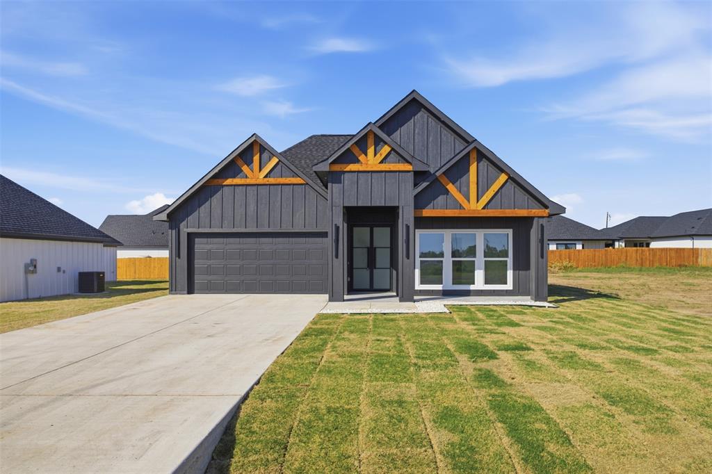Modern farmhouse exterior featuring dark vertical siding, wood-toned gable accents, a multi-gabled roofline, and a concrete driveway