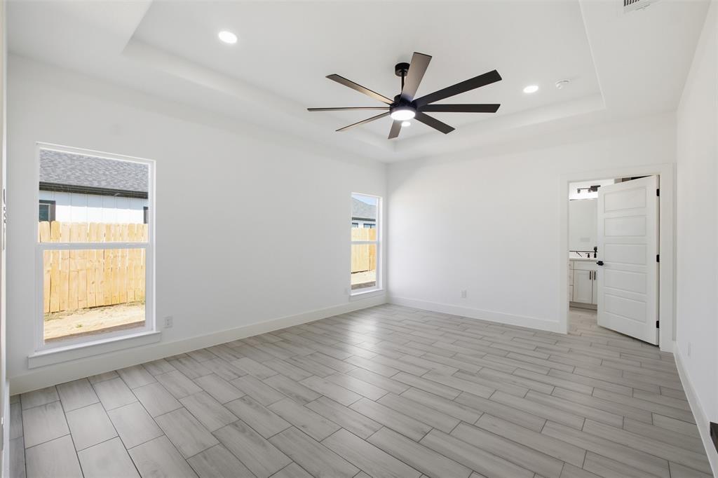 Interior space featuring a recessed tray ceiling, multi-blade ceiling fan, recessed lighting, and wood-finish tile flooring