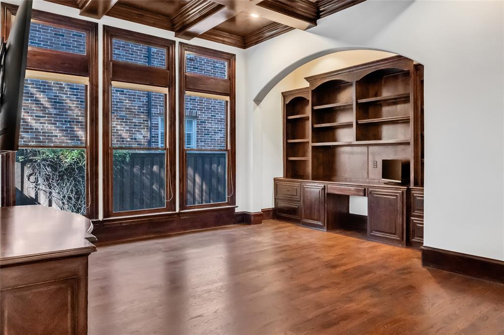 Custom built-in wood cabinetry, coffered wood ceiling, wood-finish flooring, and expansive windows with wood trim