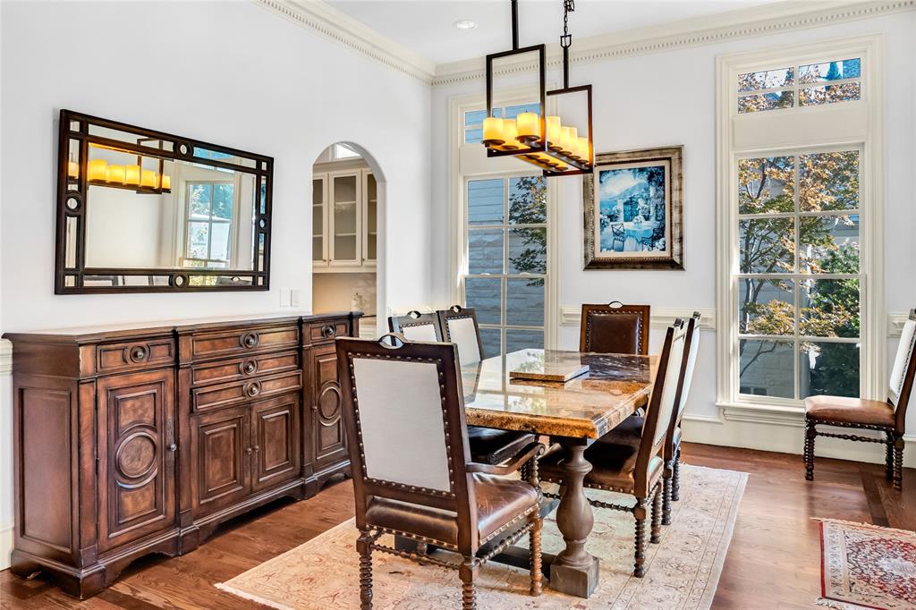 Dining area featuring wood-finish flooring, floor-to-ceiling windows with transom detailing, crown molding, and a rectangular multi-light pendant chandelier