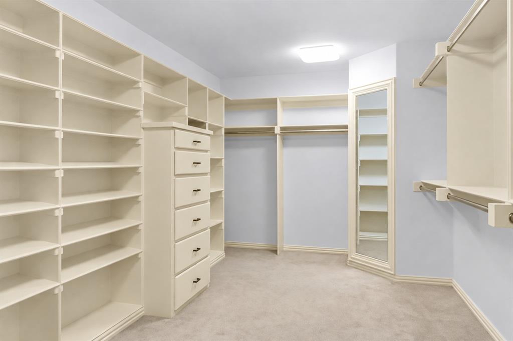 Custom closet featuring floor-to-ceiling built-in shelving, a six-drawer chest, integrated hanging rods, and a full-length beveled mirror