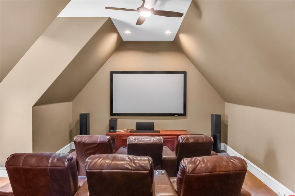 Vaulted ceilings with recessed lighting, an integrated ceiling fan, and a wall-mounted projection screen