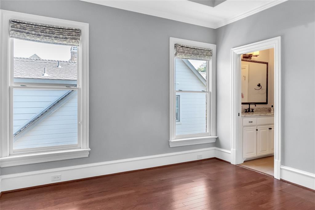 Interior space featuring wood-finish flooring, tall windows with crisp white casing, and crown molding