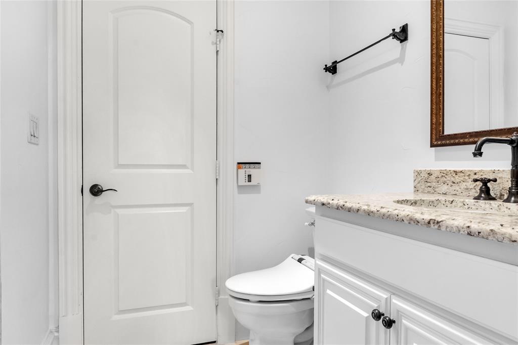 Vanity featuring a stone countertop, under-mount sink, and dark metal hardware, paired with a wall-mounted towel bar and a multi-panel interior door