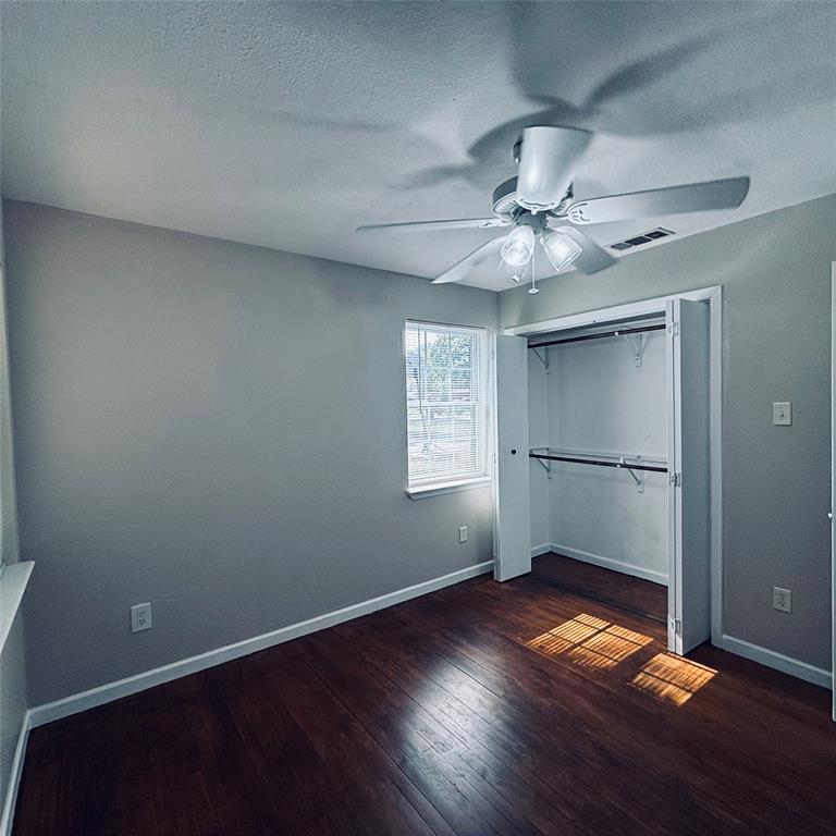 Room featuring wood-finish flooring, a multi-light ceiling fan, a window with muntins, and a closet with bifold doors