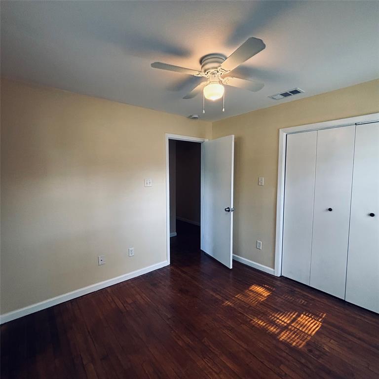 Room featuring wood-finish flooring, a ceiling fan with integrated lighting, and a multi-panel closet with matte black hardware