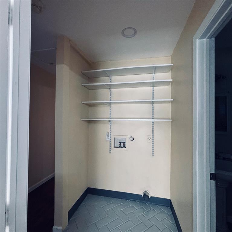 Utility space featuring herringbone-patterned tile flooring, integrated wall-mounted shelving, and recessed ceiling lighting