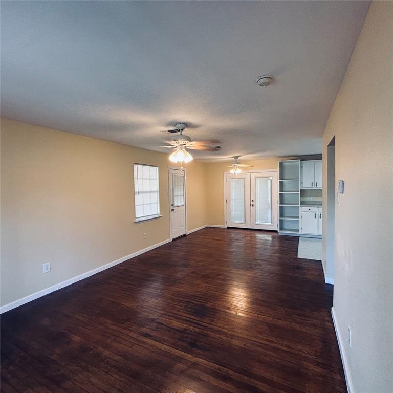 Wood-finish flooring, dual ceiling fans with light kits, built-in floor-to-ceiling cabinetry, and glass-paneled double doors