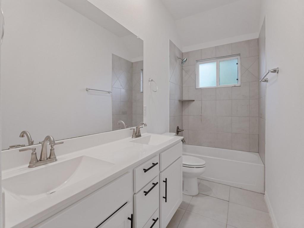 Additional bathroom featuring dual sinks and a tub and shower combination