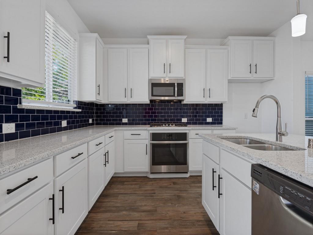 Beautiful kitchen featuring white cabinetry, granite countertops, stainless steel appliances, and a large island Beautiful kitchen featuring white cabinetry, granite countertops, stainless steel appliances, and a large island