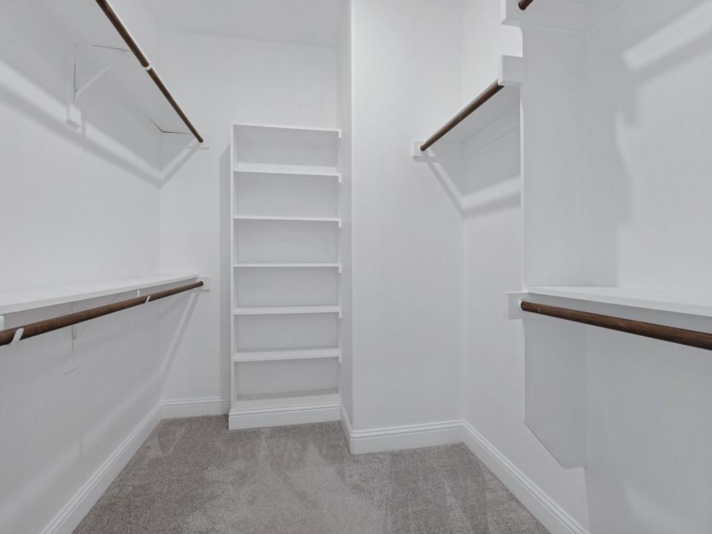 Generous walk-in closet with built-in shelving and multiple hanging areas
