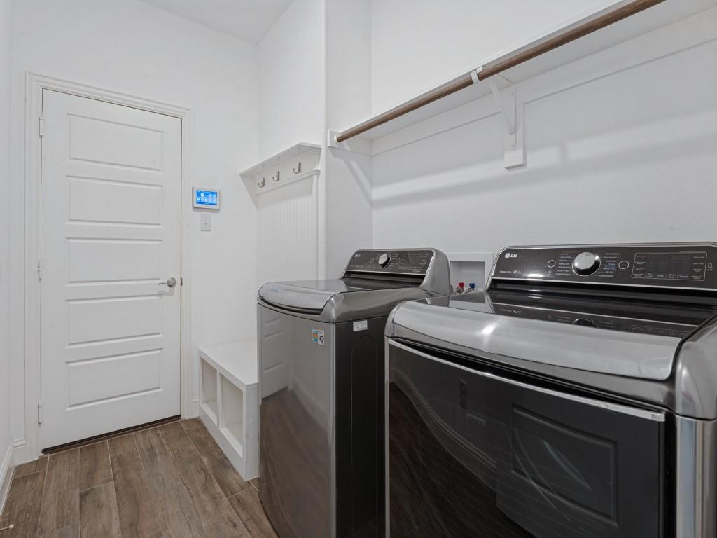 Dedicated laundry room with overhead shelving and space for a full-size washer and dryer
