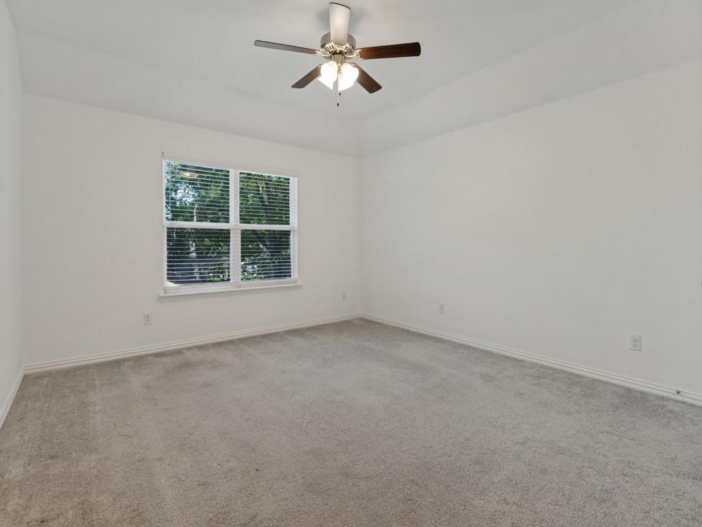 Comfortable bedroom featuring soft carpeting, a ceiling fan, and natural light.