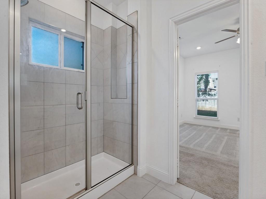 Spacious primary shower with tile surround and a glass enclosure.