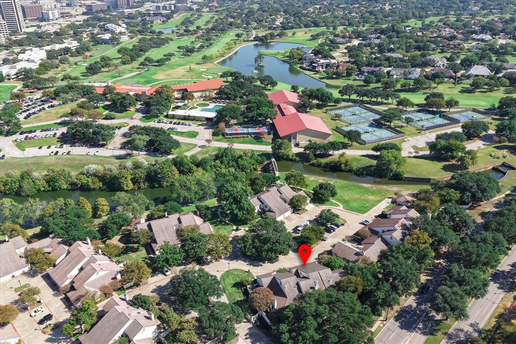 Aerial perspective of a multi-unit residential complex featuring gabled rooflines, mature shade trees, and proximity to a waterway and public recreational facilities
