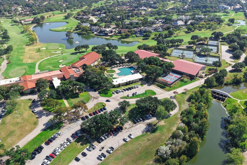 Aerial view of a sprawling complex featuring multiple swimming pools, tennis courts, red-tile roofing, and expansive grounds situated along a water feature and golf course