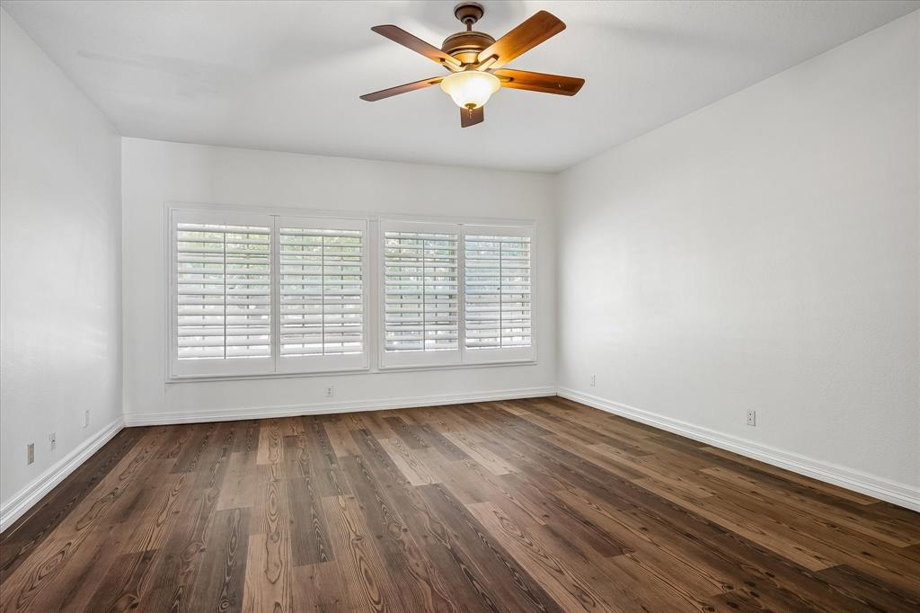 Primary bedroom , plantation shutters, and a central ceiling fan with an integrated light fixture