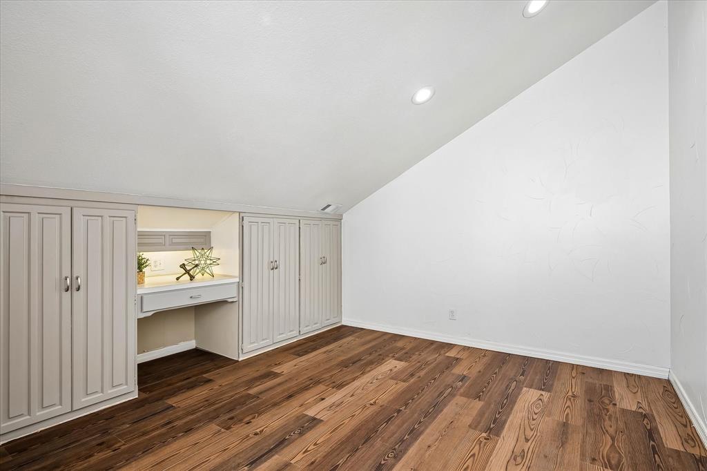 Sloped ceiling featuring recessed lighting, wood-finish flooring, and built-in cabinetry with an integrated desk