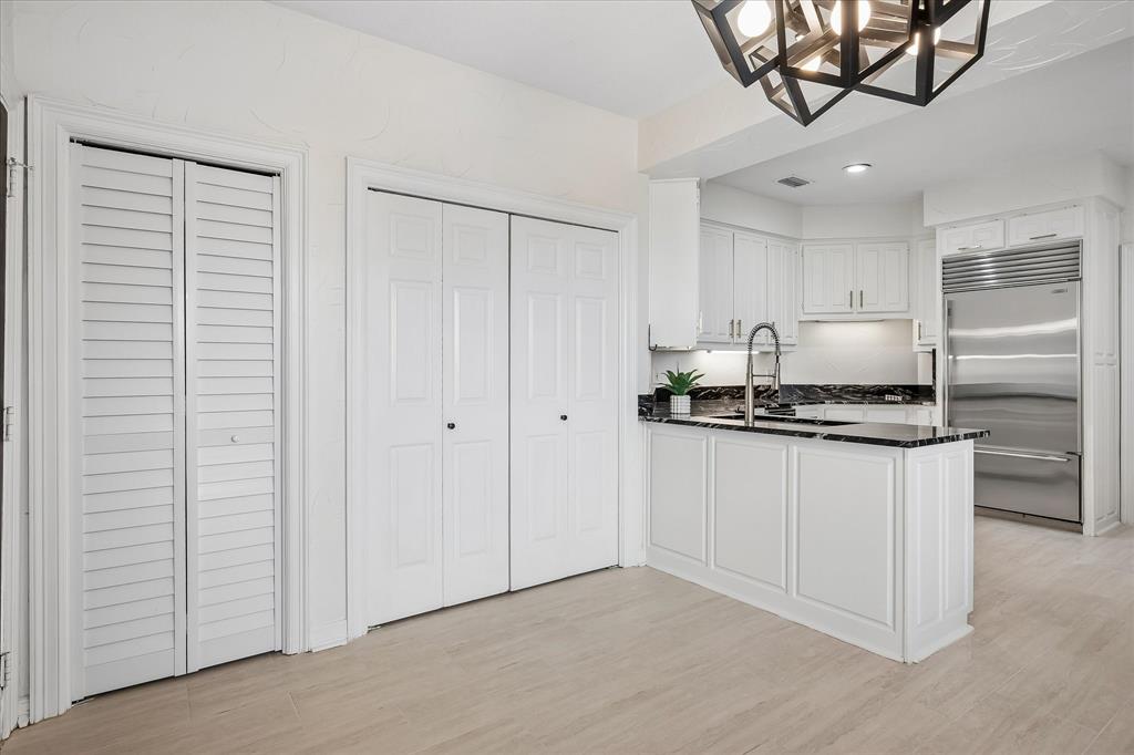 Geometric multi-light pendant fixture, white plantation shutters, wood-finish flooring, and crisp white panel doors