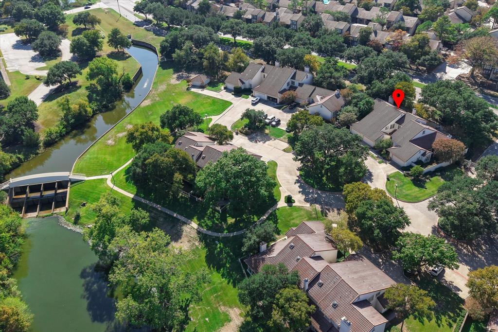 Aerial perspective of walkway to the Las Colinas Country Club featuring mature trees, expansive green space, and proximity to a waterway with a pedestrian bridge