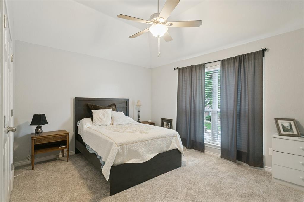 Vaulted ceiling, neutral wall tones, neutral carpeting, and a multi-blade ceiling fan with integrated lighting