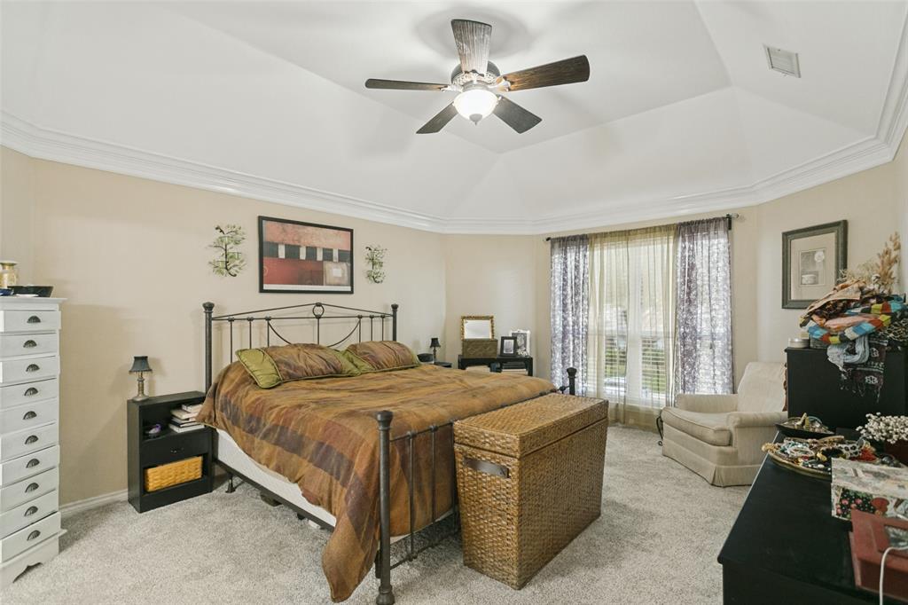 Tray ceiling with crown molding, ceiling fan with integrated lighting, neutral wall palette, and carpeted flooring