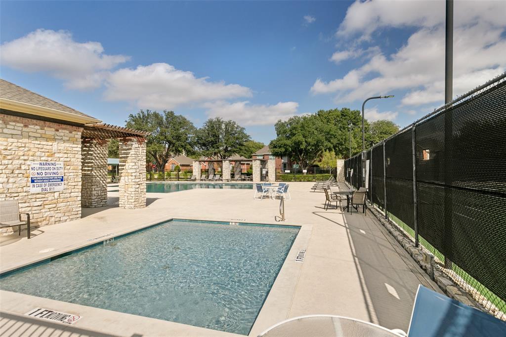 Swimming pool with stone-veneer accent wall, pergola-covered deck area, and enclosed tennis court