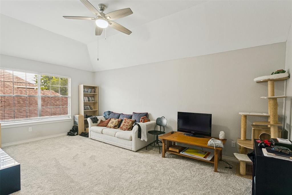 Vaulted ceilings, neutral wall tones, wall-to-wall carpeting, and a multi-blade ceiling fan with integrated lighting