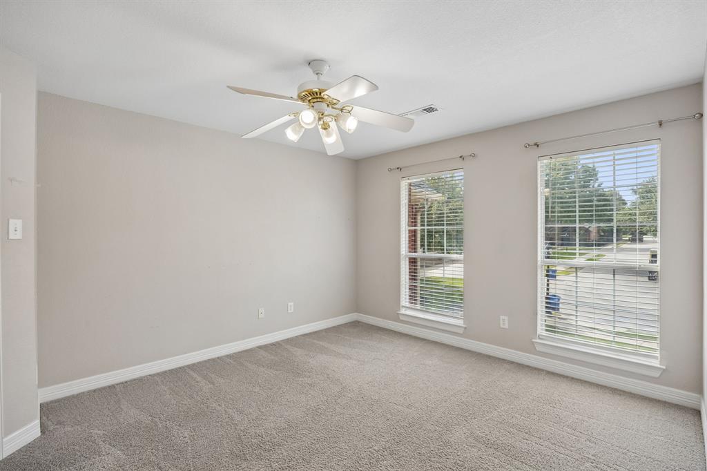Neutral-toned interior space featuring neutral wall-to-wall carpeting, two dual-pane windows with horizontal blinds, and a white ceiling fan with integrated multi-bulb lighting