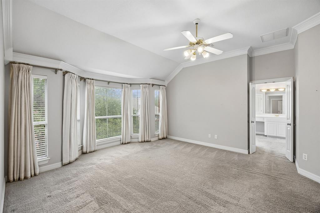 Vaulted ceilings, bay window configuration, neutral wall finishes, carpeted flooring, and a multi-light ceiling fan