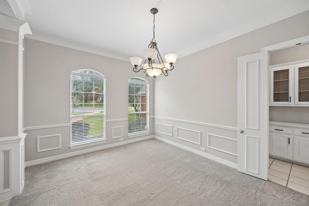 Room featuring decorative wall molding, arched-top windows, crown molding, a multi-light chandelier, and built-in cabinetry