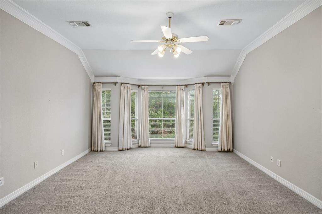 Vaulted ceilings, expansive bay window, ceiling fan with integrated lighting, and neutral carpeting