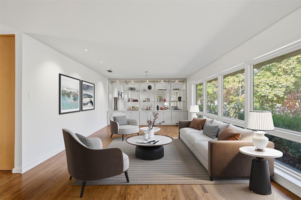 Expansive room featuring wood-finish flooring, recessed lighting, floor-to-ceiling windows, and built-in glass-front cabinetry with integrated shelving.