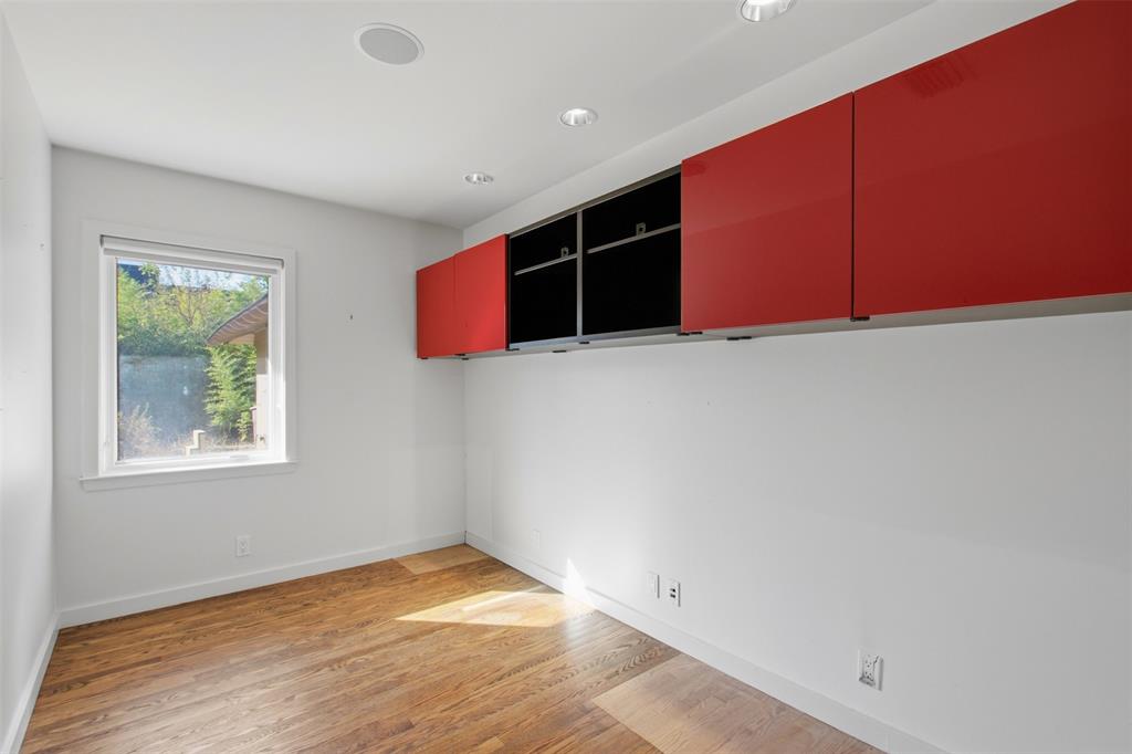 Wood-finish flooring, recessed ceiling lighting, and wall-mounted red and black cabinetry with a high-gloss finish