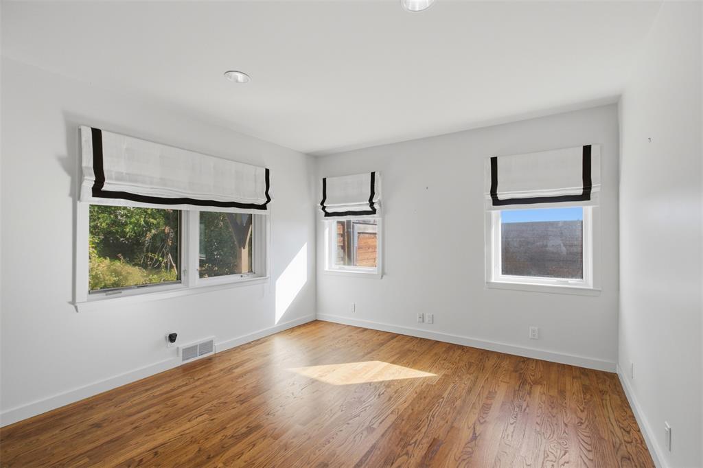 Wood-finish flooring, recessed ceiling lighting, and multiple windows with white trim